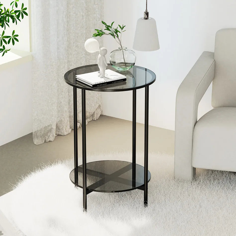 Round glass side table with black metal legs in a modern living room setting.