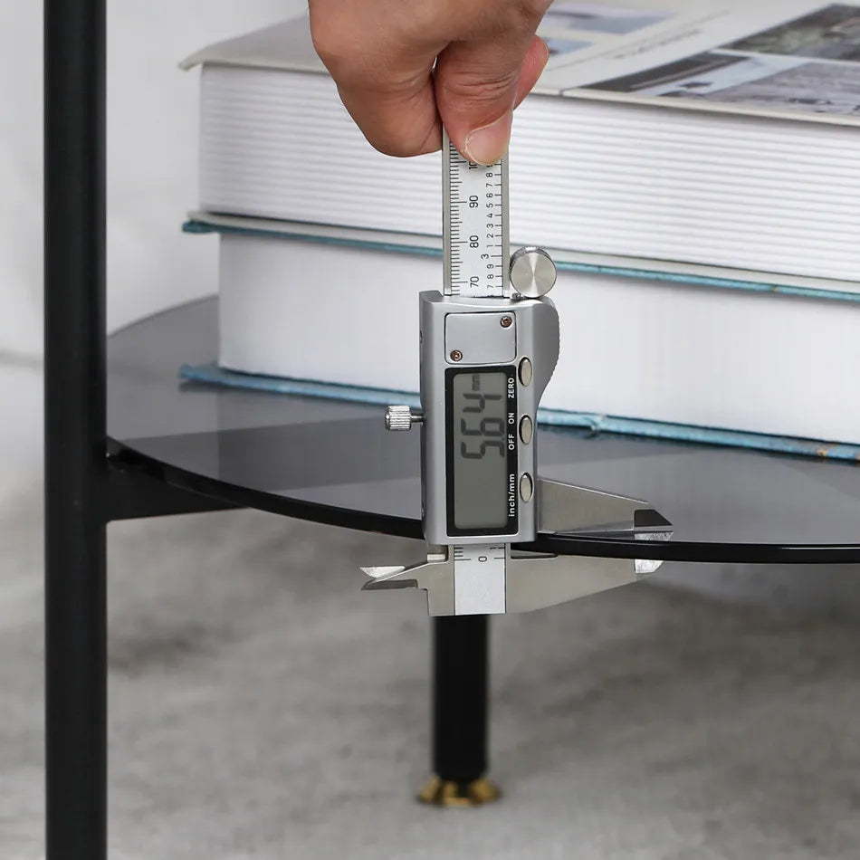 Digital caliper measuring a glass table with books in the background