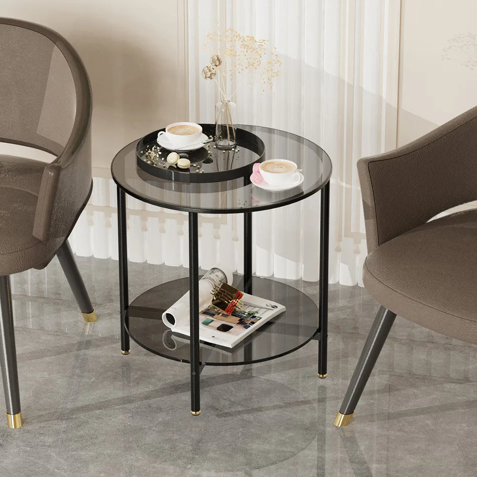 Round glass side table with black metal frame in a room setting with chairs and decor items.