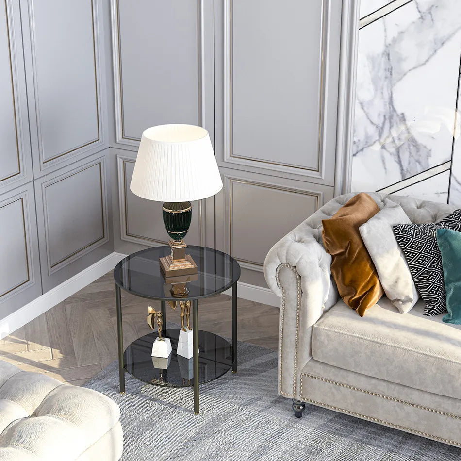 Modern living room with a gray sofa, glass side table, and decorative lamp.