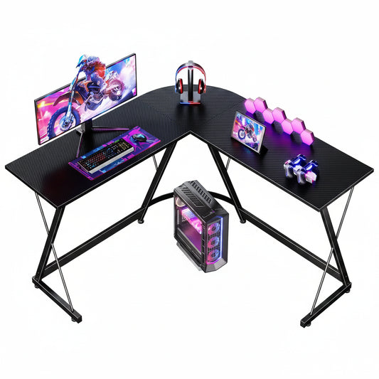 Black L-shaped gaming desk with computer setup including monitor, keyboard, and RGB components.