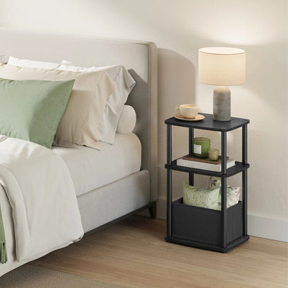 Black nightstand with lamp and decor items next to a bed in a bedroom.