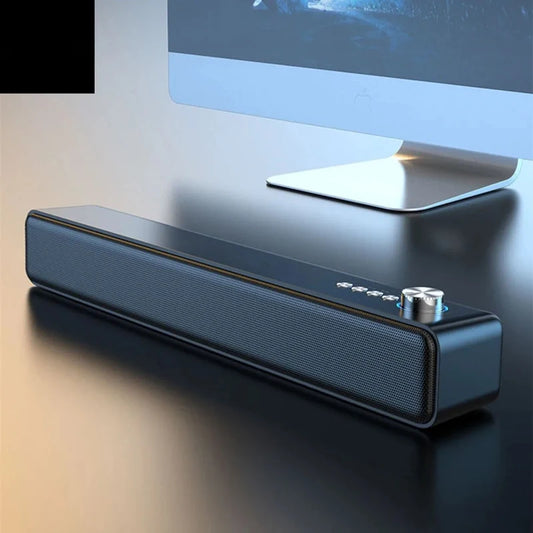 Black soundbar on a desk with a computer monitor in the background
