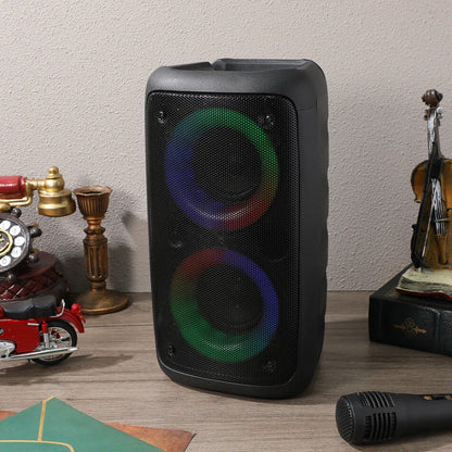 Black speaker with colorful lights on a wooden surface with decorative items.