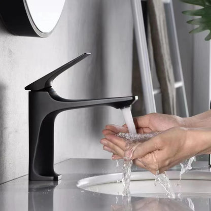 Person washing hands under a black faucet in a modern bathroom setting.