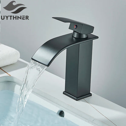 Black faucet with water flowing into a sink, branded 'UYTHNER'.