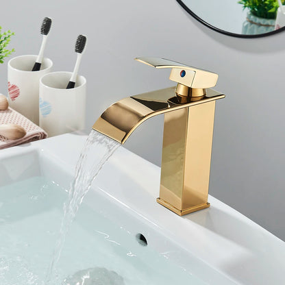 Gold faucet on a sink with cups and toothbrushes in the background