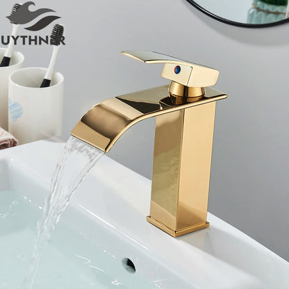 Gold faucet on a sink with water flowing, branded 'UYTHNER'.