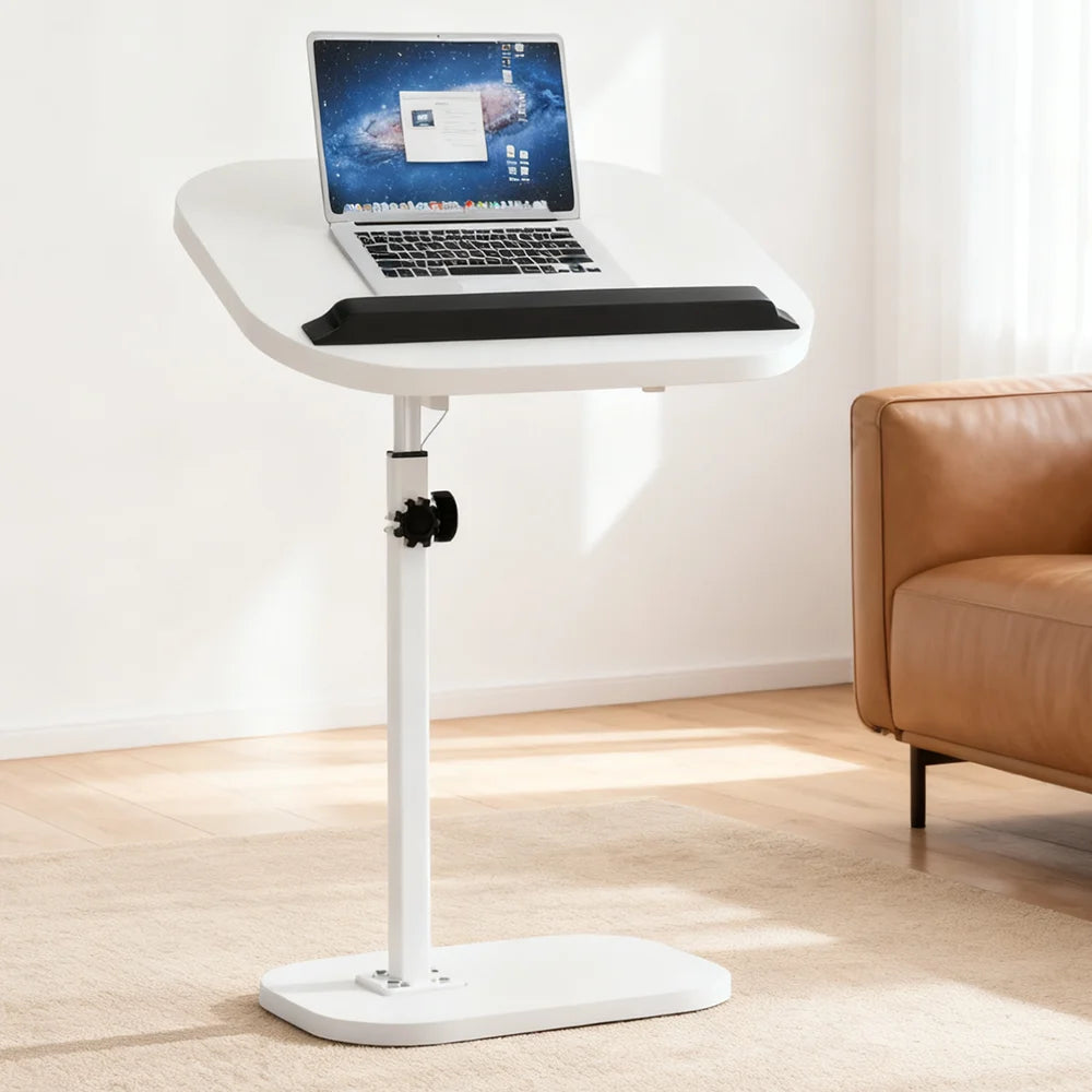 White adjustable laptop stand with a laptop on top in a room with a brown couch.