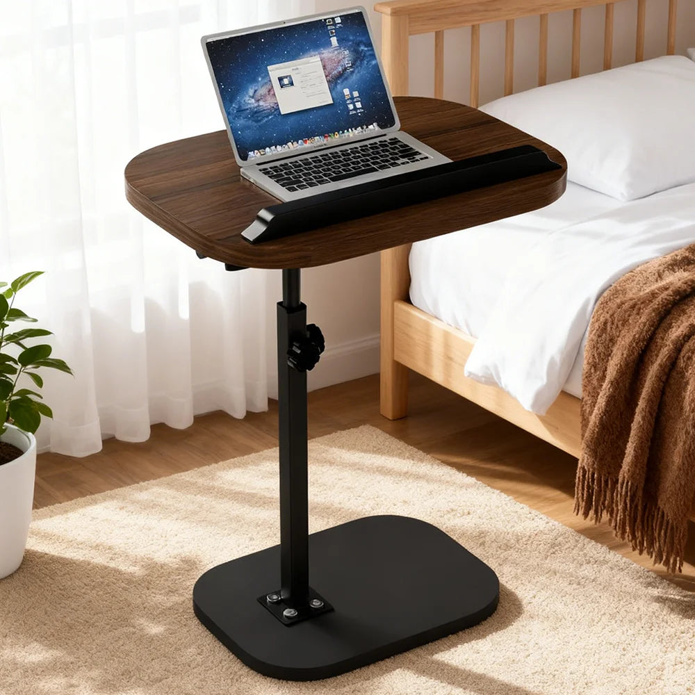 Wooden adjustable laptop desk in a bedroom setting with a laptop on top.