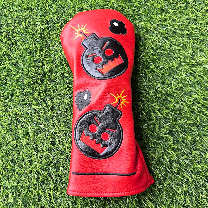 Red golf club head cover with black and yellow designs on a grass background