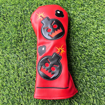 Red golf club head cover with black and yellow designs on a grass background