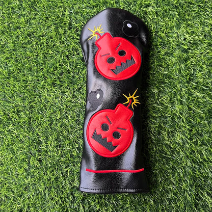 Black golf club head cover with red bomb designs on a grass background