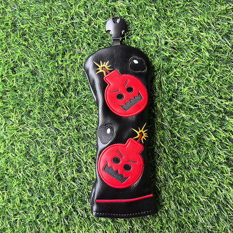 Black golf club head cover with red bomb design on a grass background