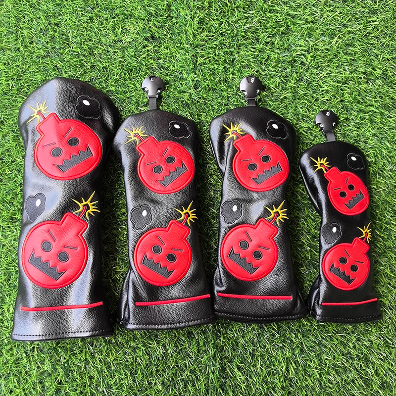 Four black golf club head covers with red bomb designs on a grass background