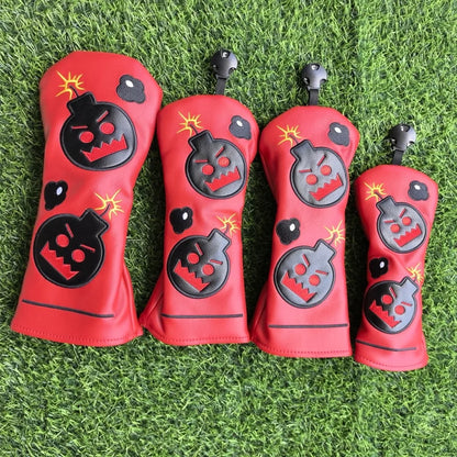 Four red golf club head covers with black and gray designs on a grass background