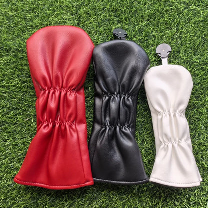 Red, black, and white golf club head covers on grass