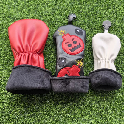 Three golf club heads with covers on a grass background