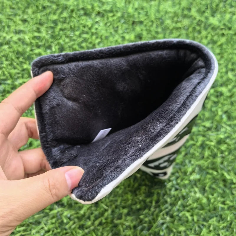 Hand holding a black and white pet toy on grass