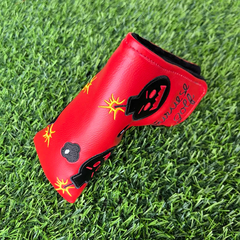 Red golf club head cover with black and yellow design on grass
