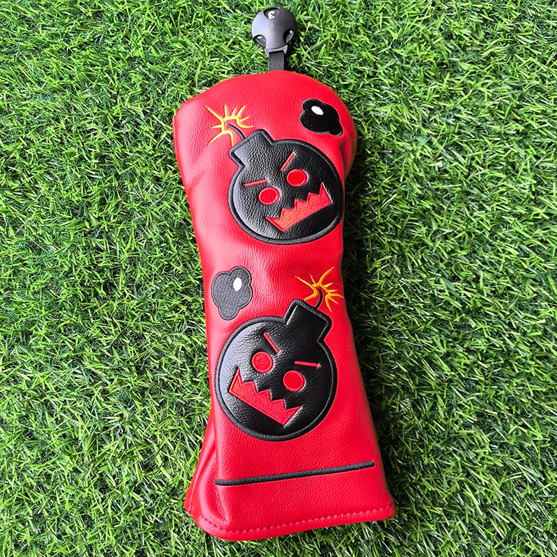 Red golf club head cover with black designs on a grass background