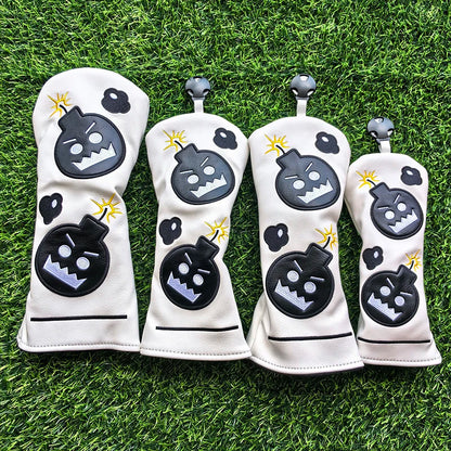 Four white golf club head covers with black and gray designs on a grass background