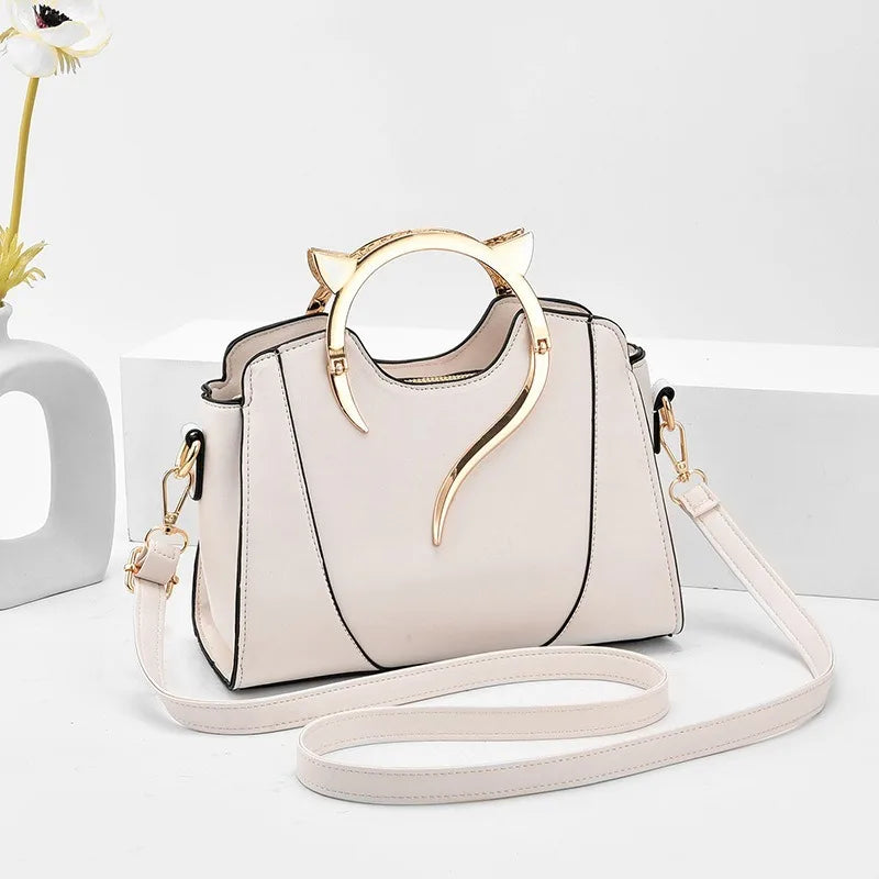 White handbag with gold cat ear handles on a light gray background
