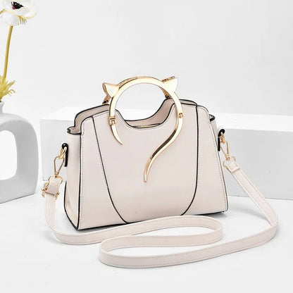 White handbag with gold cat ear handles on a light gray background