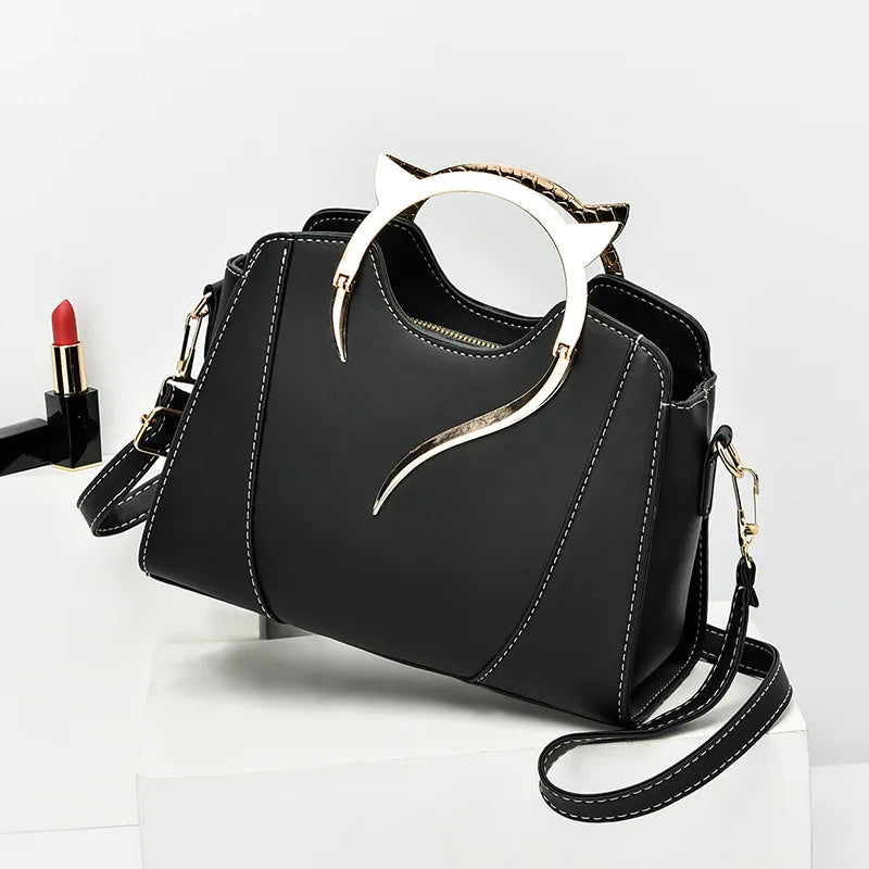 Black handbag with decorative handle on a white background