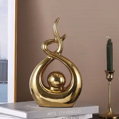 Gold decorative sculpture on a book with a candle holder in the background