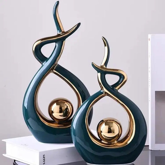 Two decorative sculptures with gold accents on a light gray background