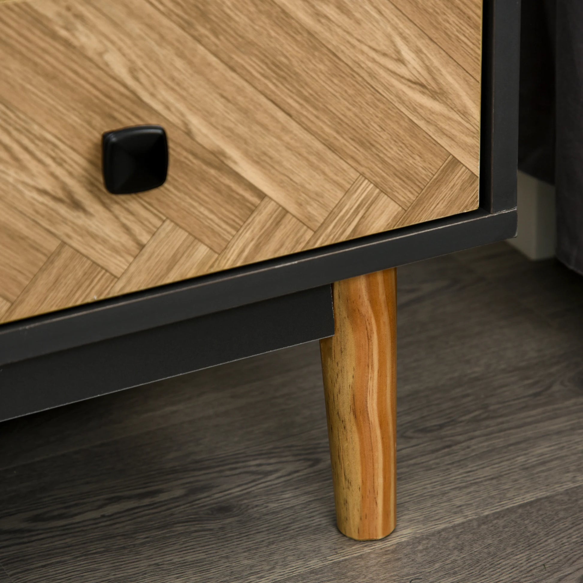 Wooden furniture leg and drawer with a black handle on a wooden floor.