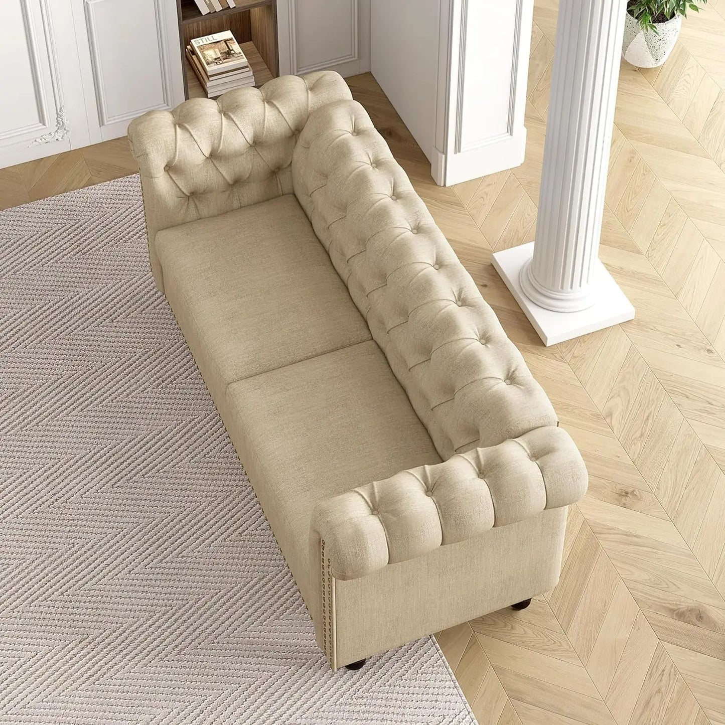 Beige tufted sofa in a room with wooden flooring and a rug.