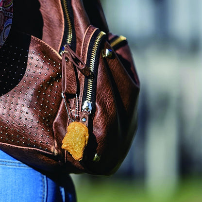Brown leather backpack with a yellow keychain on a blurred background