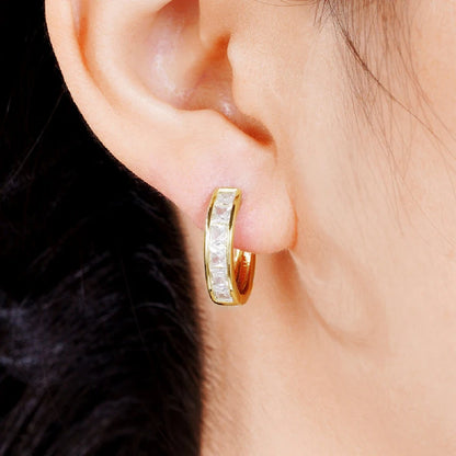 Gold hoop earring with embedded stones worn by a person