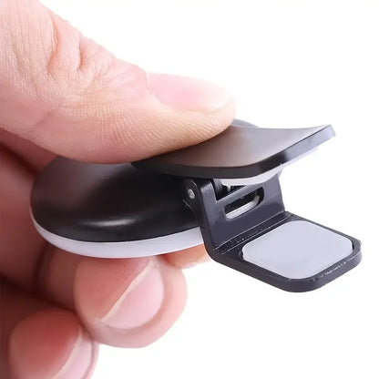 Black and white clip held between fingers on a white background