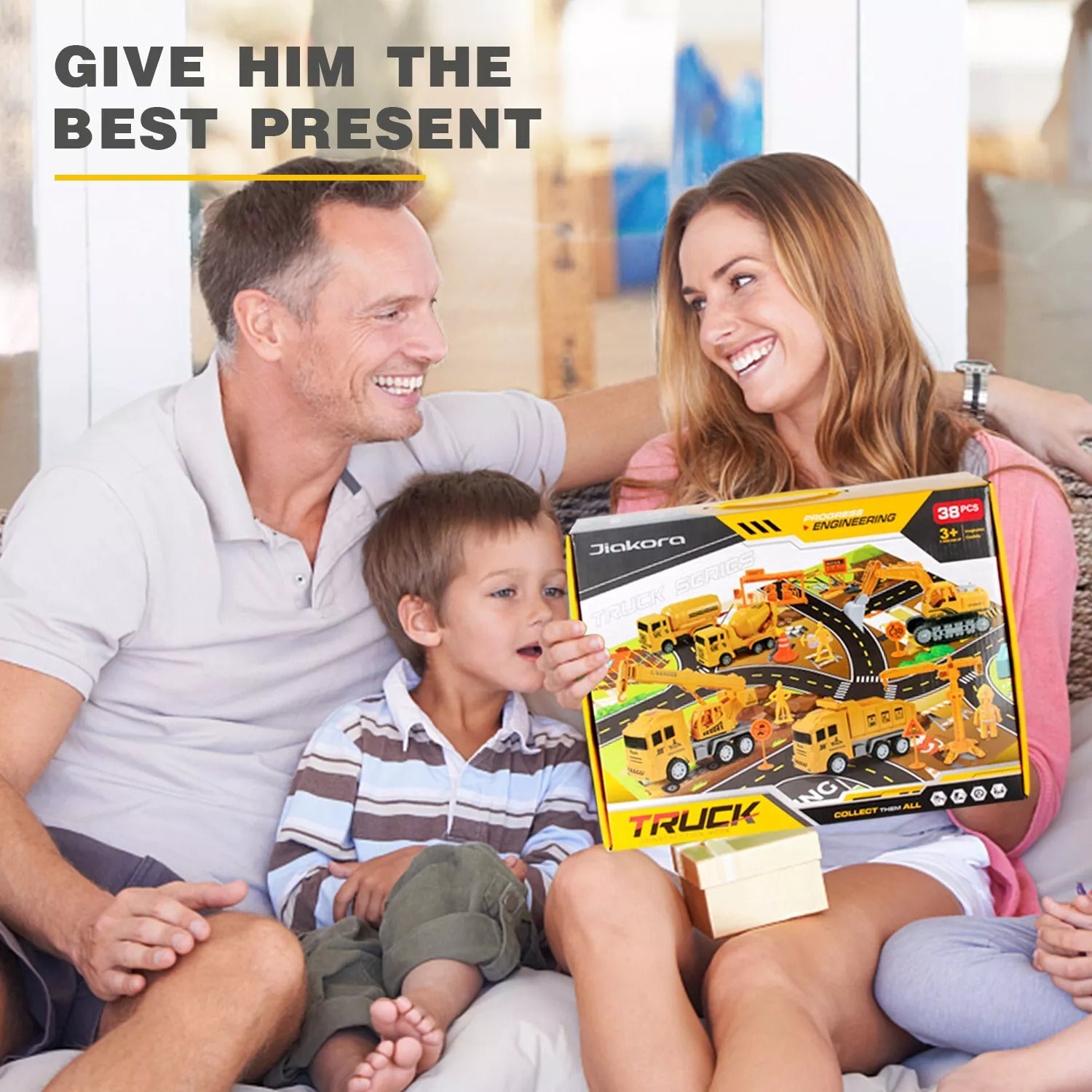 Family of three with a toy truck set packaging, sitting on a couch.