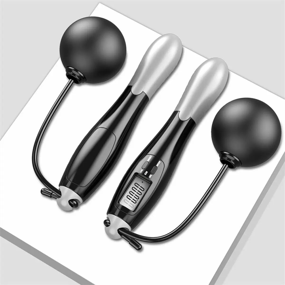 Two black and silver massage sticks with digital display on a white surface
