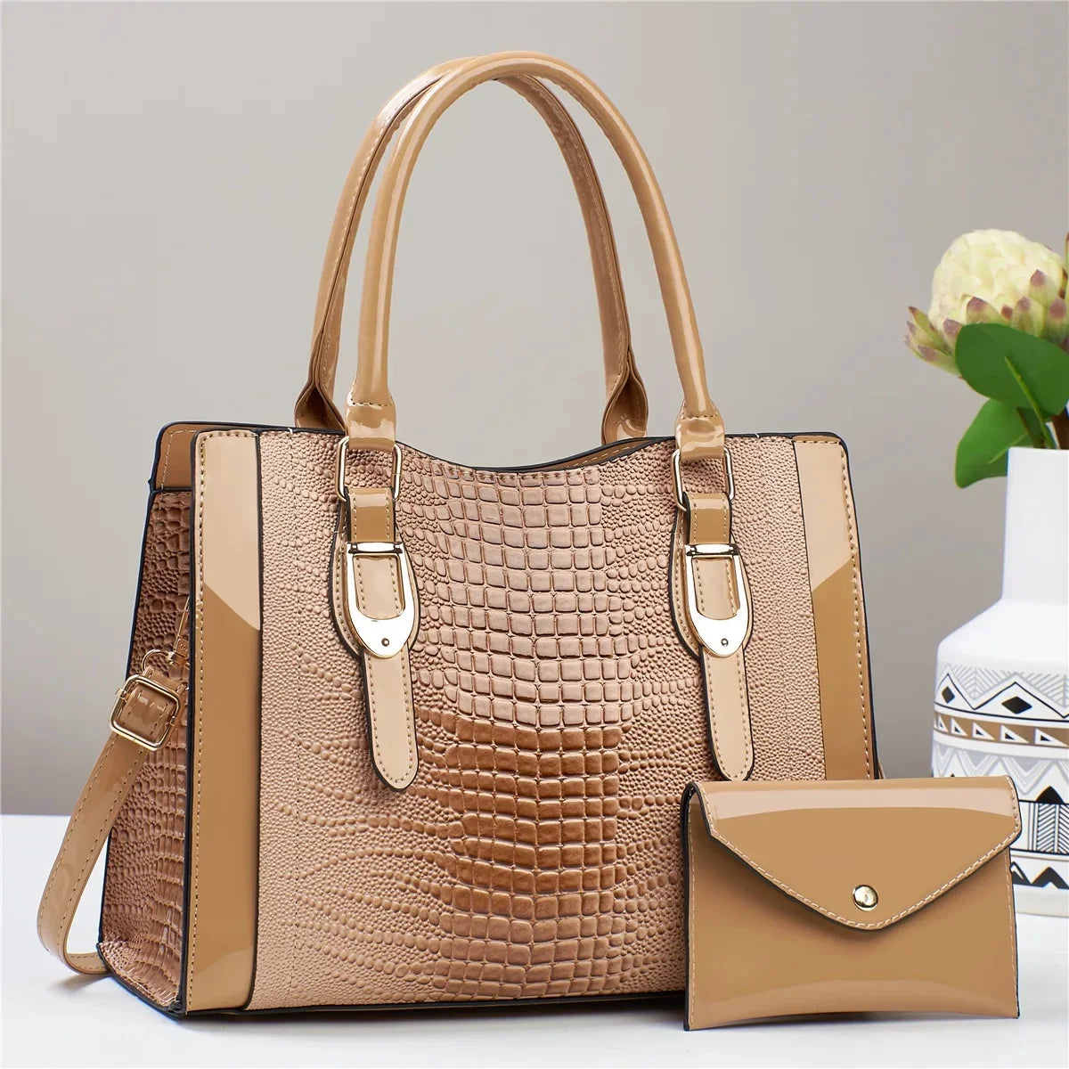 Tan handbag with crocodile texture and matching pouch on a light gray background
