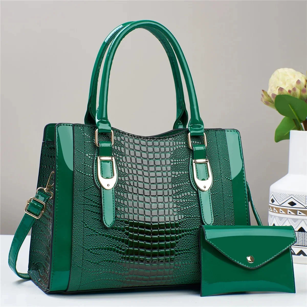 Green handbag with matching pouch on a light gray background