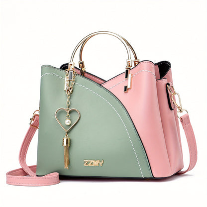 Two-tone pink and green handbag with a heart-shaped keychain on a white background