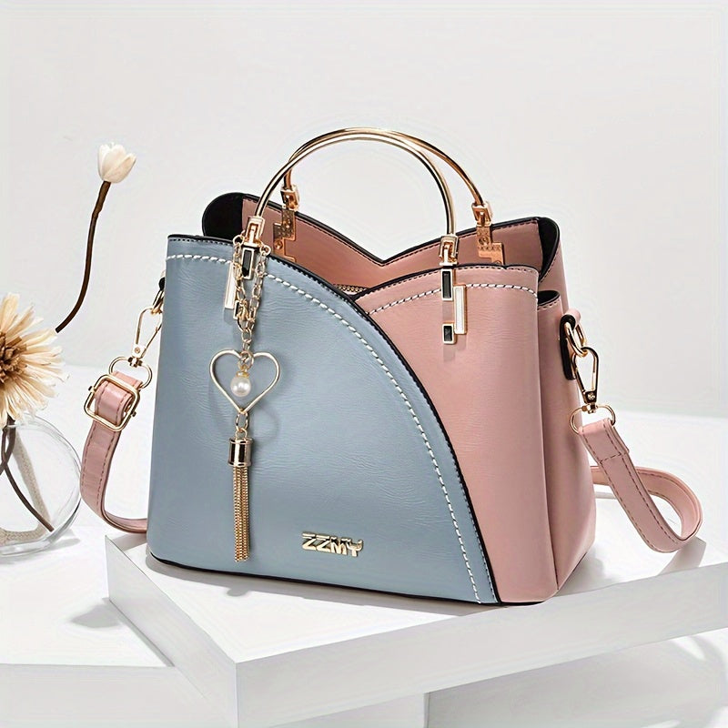 Two-tone blue and pink handbag with heart-shaped keychain on a white surface.