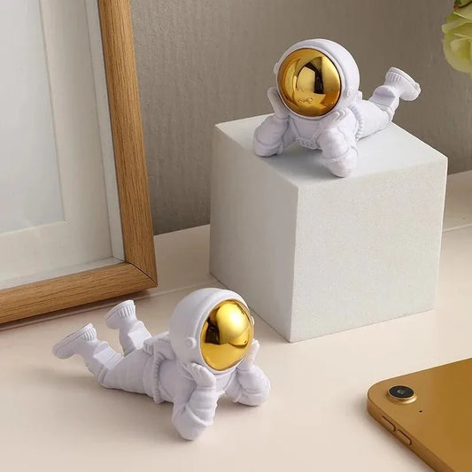 White astronaut figurines with gold heads on a white surface.