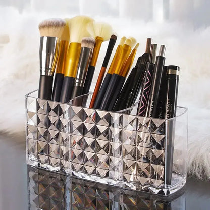 Makeup brushes in a decorative holder on a reflective surface with a blurred background