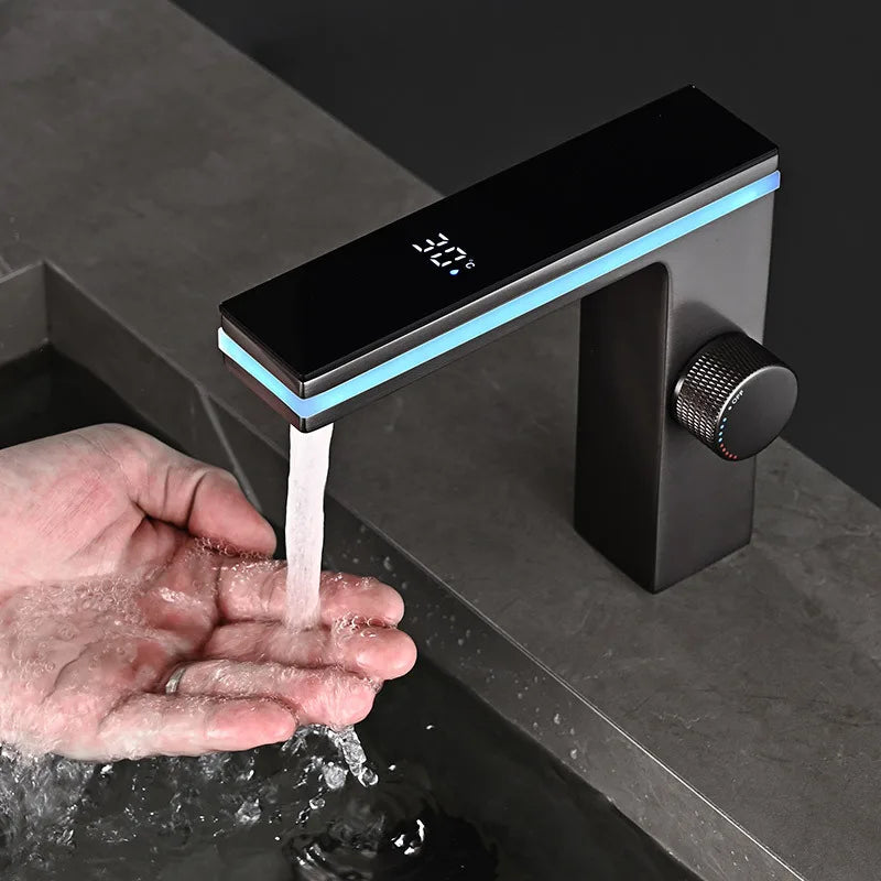Black faucet with digital display and water flowing into a hand under a dark countertop.