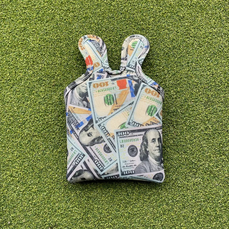 Small pouch with dollar bill pattern on a green grass background