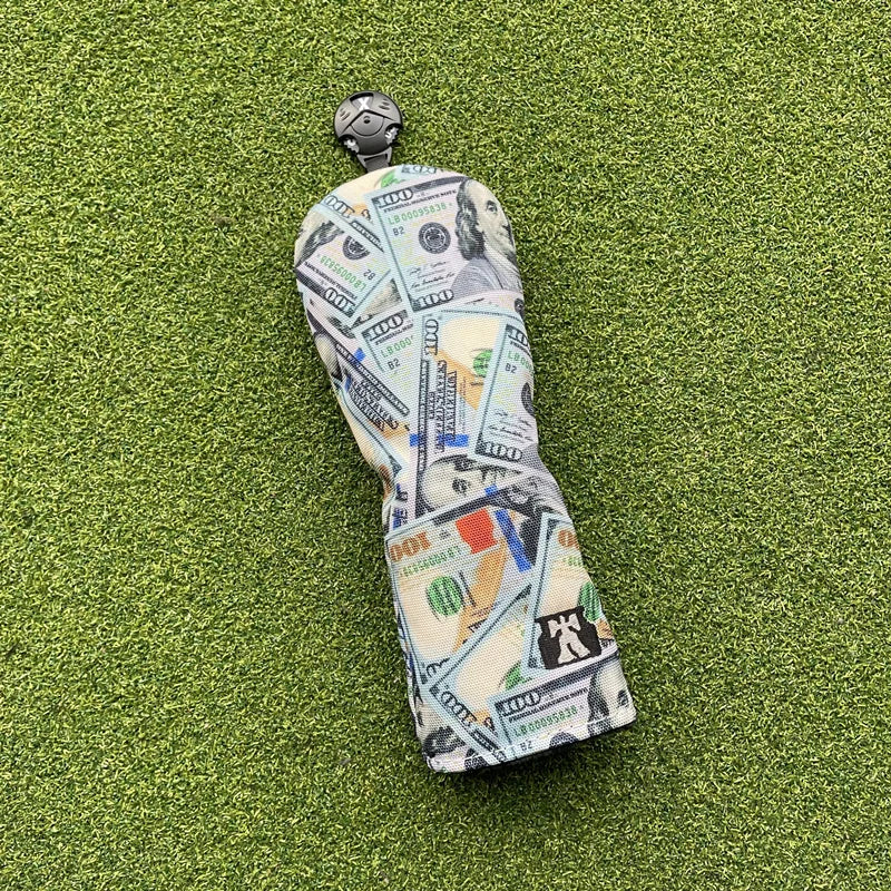 Golf club head cover with dollar bill pattern on a green surface