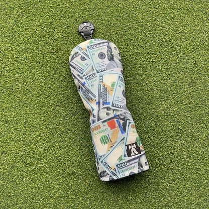 Golf club head cover with dollar bill pattern on a green surface