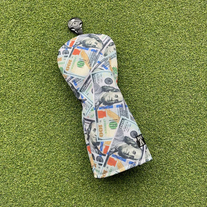 Golf club head cover with dollar bill design on a green surface