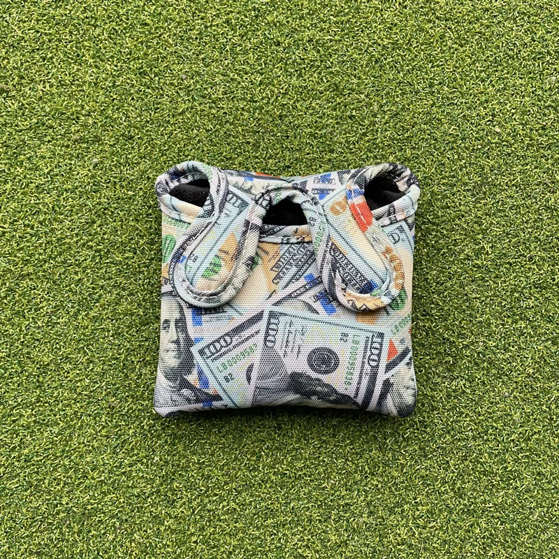 Golf ball marker with dollar bill design on a green surface